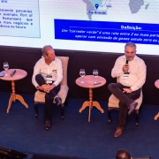 Foto mostra palestrantes no palco, sentados, durante debate.