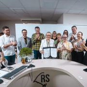 Foto mostra secret&aacute;ria Arita Bergmann com um documento nas m&atilde;os e outras pessoas posando ao lado dela aplaudindo o ato.