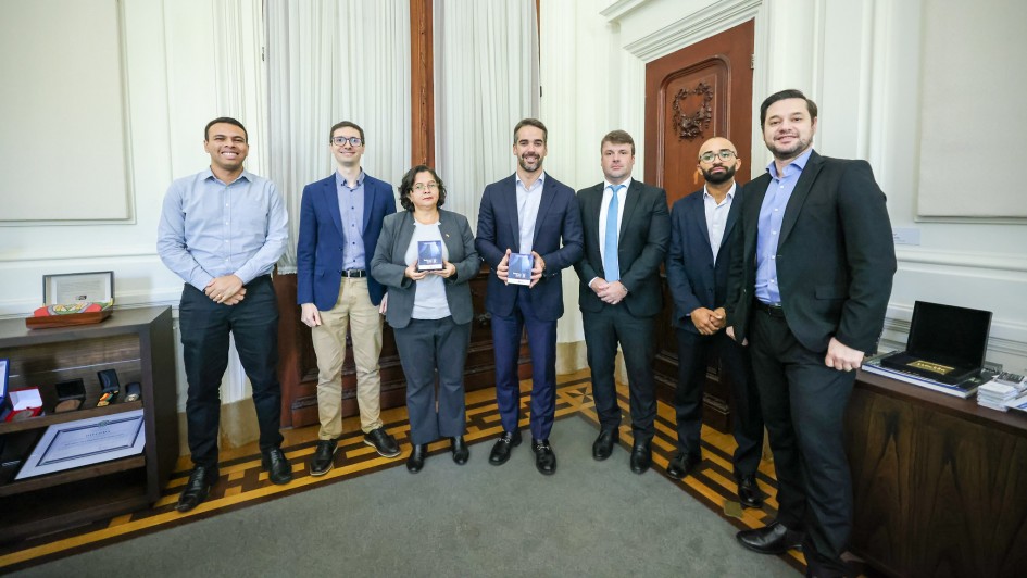 Foto mostra o governador Eduardo Leite com a secret&aacute;ria da Fazenda, Pricilla Santana, o contador e auditor-geral do Estado, Carlos Geminiano Rodrigues, e equipe da Contadoria e Auditoria-Geral do Estado (Cage). Governador e secret&aacute;ria asseguram exemplares do Balan&ccedil;o Geral do Estado nas m&atilde;os. 