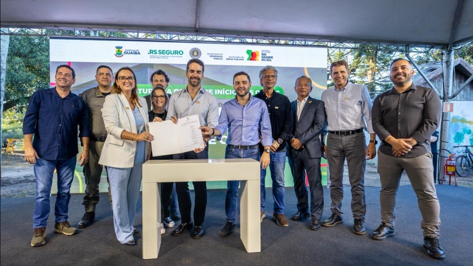 Foto mostra o governador Eduardo Leite e a prefeita segurando um documento. O vice-governador Gabriel Souza e outras autoridades acompanham o ato.