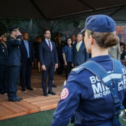 Foto mostra o governador Eduardo Leite no centro da foto. Militares fazem contin&ecirc;ncia para ele. Em primeiro plano, de costas para a c&acirc;mera, uma bombeiro militar fardada, tamb&eacute;m est&aacute; direcionada para ele.