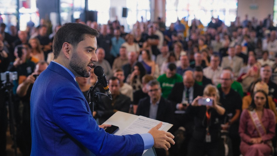 Homem discursa para uma plateia em uma &aacute;rea coberta