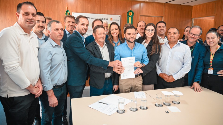 Foto mostra o vice-governador Gabriel Souza exibindo o termo assinado, cercado por comitiva dos munic&iacute;pios. 