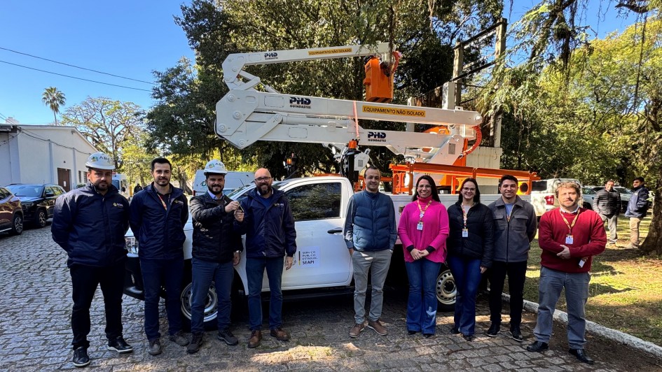 Registro coletivo ao ar livre, com grupo posicionado em frente a ve&iacute;culo utilit&aacute;rio equipado com plataforma elevat&oacute;ria e cesto a&eacute;reo.