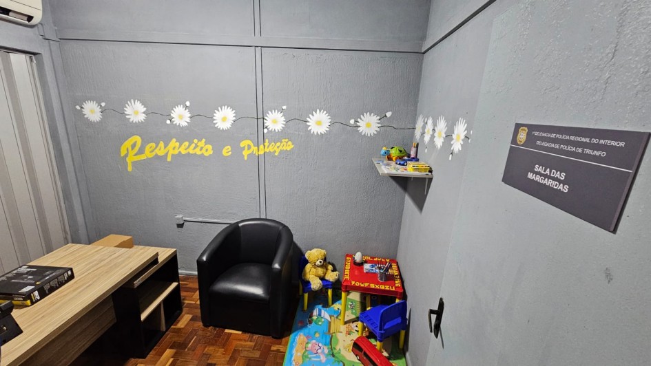 Sala de atendimento identificada como &ldquo;Sala das Margaridas&rdquo;, com decora&ccedil;&atilde;o acolhedora e tem&aacute;tica infantil. O espa&ccedil;o inclui poltrona, mesa de trabalho, brinquedos, tapete colorido e prateleira com objetos. Na parede, h&aacute; o texto &ldquo;Respeito e Prote&ccedil;&atilde;o&rdquo; em amarelo, al&eacute;m de flores decorativas.