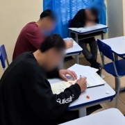 Foto mostra estudantes em uma sala de aula, realizando uma prova. Os rostos est&atilde;o com um efeito que borra o rosto.
