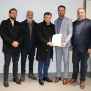 Foto mostra secret&aacute;rio e representantes da Microempa durante assinatura documento.