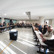 Foto mostra sala da reuni&atilde;o da Defesa Civil com a Famurs. Todos est&atilde;o dispostos com suas mesas em formato de U.