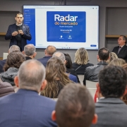 Foto mostra um dos respons&aacute;veis pelo programa apresentando a iniciativa, diante da plateia. 