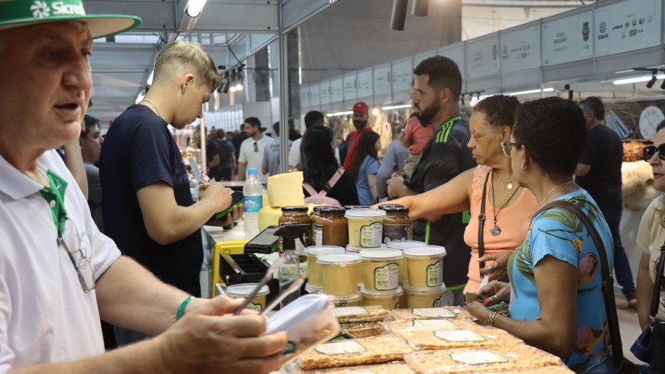 Foto do Pavilh&atilde;o da Agricultura Familiar mostra feirantes e p&uacute;blico na feira. 