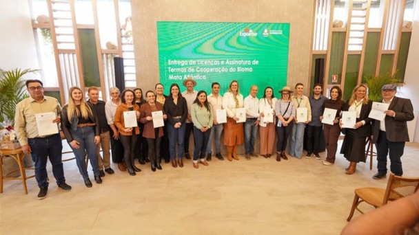 Foto mostra grupo posando para foto, exibindo documentos das licen&ccedil;as.