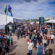 Imagem mostra grande p&uacute;blico na principal entrada da Expointer, com v&aacute;rios toldos de tendas nas laterais.