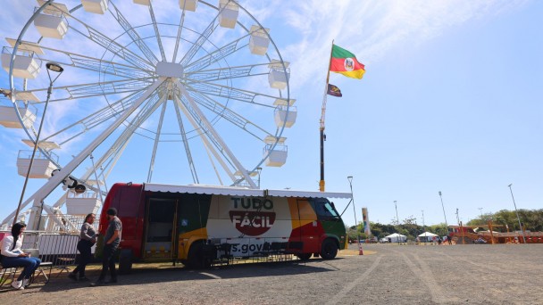 Foto mostra a unidade do Tudo F&aacute;cil no p&aacute;tio do Acampamento Farroupilha. Ao fundo, aparece a roda gigante. O c&eacute;u est&aacute; azul.