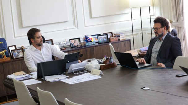Foto mostra o governador Eduardo Leite em reuni&atilde;o com o secret&aacute;rio-executivo do Programa RS Seguro, delegado Ant&ocirc;nio Padilha. Eles est&atilde;o sentados numa mesa de reuni&atilde;o, com notebooks a frente deles. 